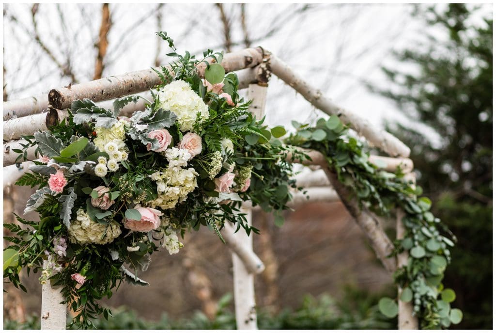Branch and greenery arch with floral detail at Barn on Bridge holiday wedding ceremony