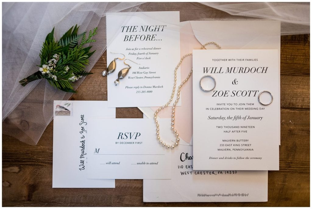 Simple black and white wedding invitation suite with wedding bands, earrings, pearl necklace and pine boutonniere
