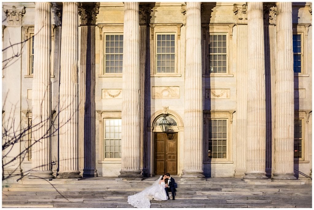 Bride and groom sit and kiss on steps at First National Bank