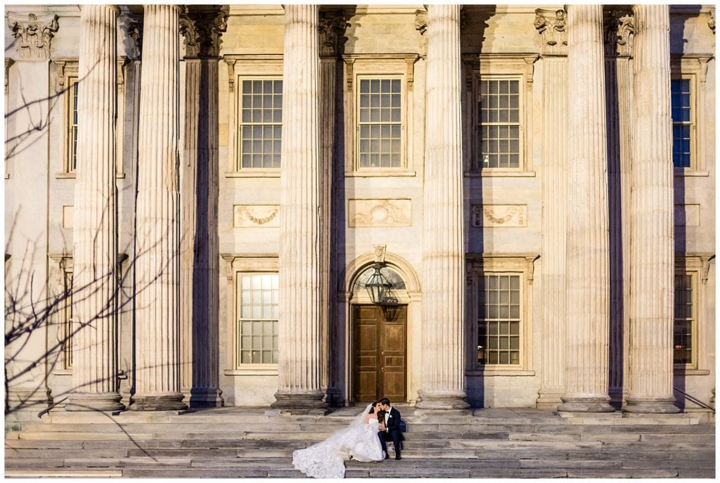 Bride and groom sit and kiss on steps at First National Bank