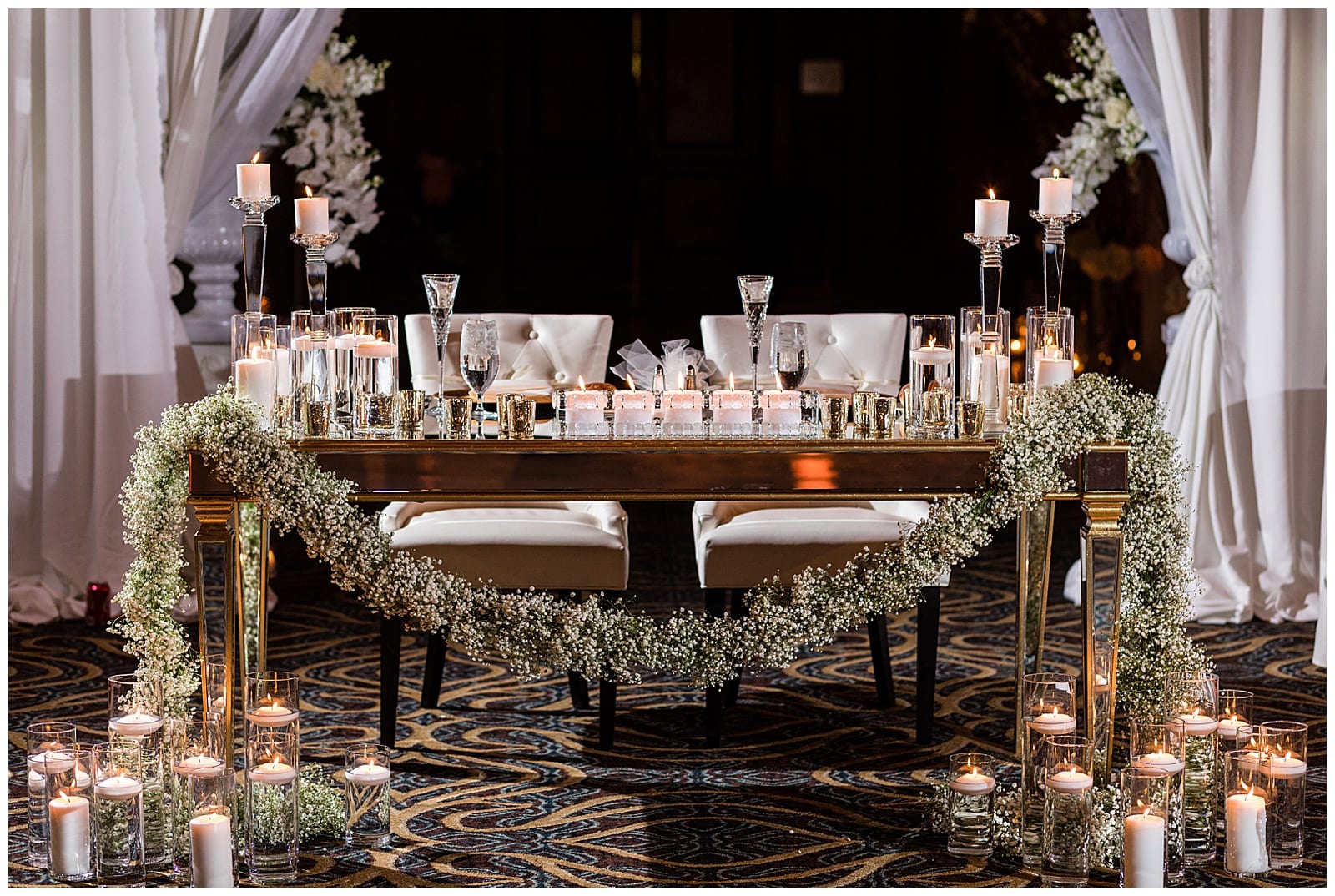 Bride and groom sweetheart table with babies breath table runner and multi-tiered candles at Crystal Tea Room wedding reception