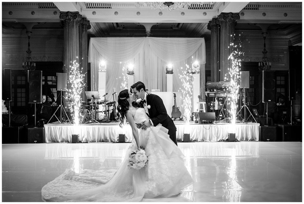 Black and white portrait of groom dipping bride on dance floor with sparklers at Crystal Tea Room wedding reception