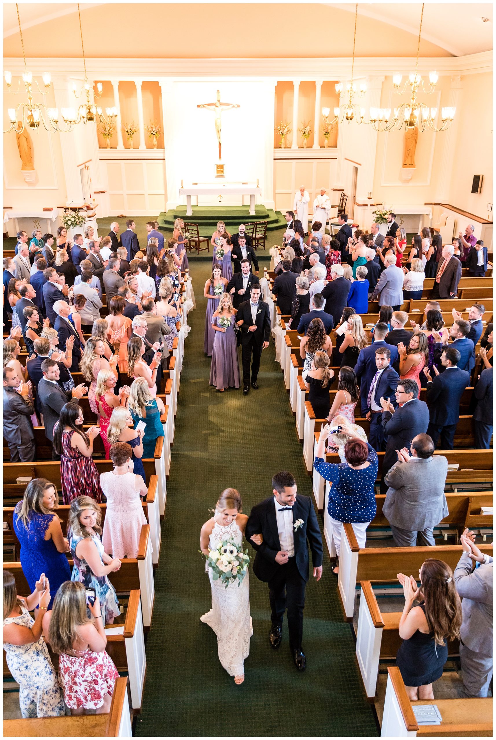 Bride and groom followed by wedding party exit church after St. James Roman Catholic Church wedding ceremony