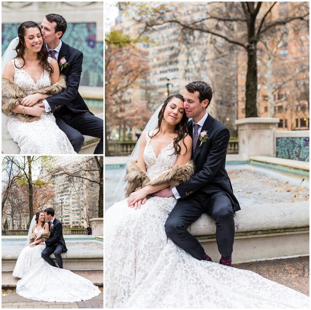 Bride and groom sit on fountain and kiss in Rittenhouse Square Park at Philadelphia winter holiday wedding