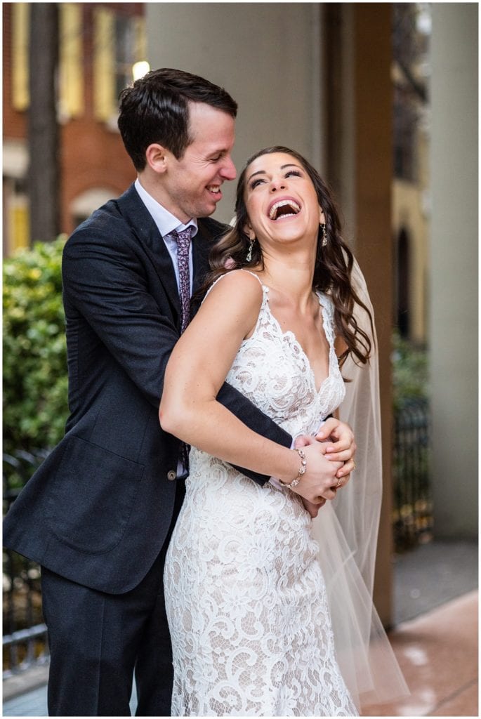 Bride laughing as groom hugs her around the waist in Philadelphia winter holiday wedding