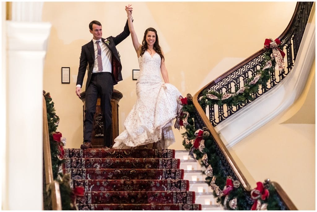 Bride and groom enter from staircase to introduction at Racquet Club of Philadelphia winter holiday wedding ceremony