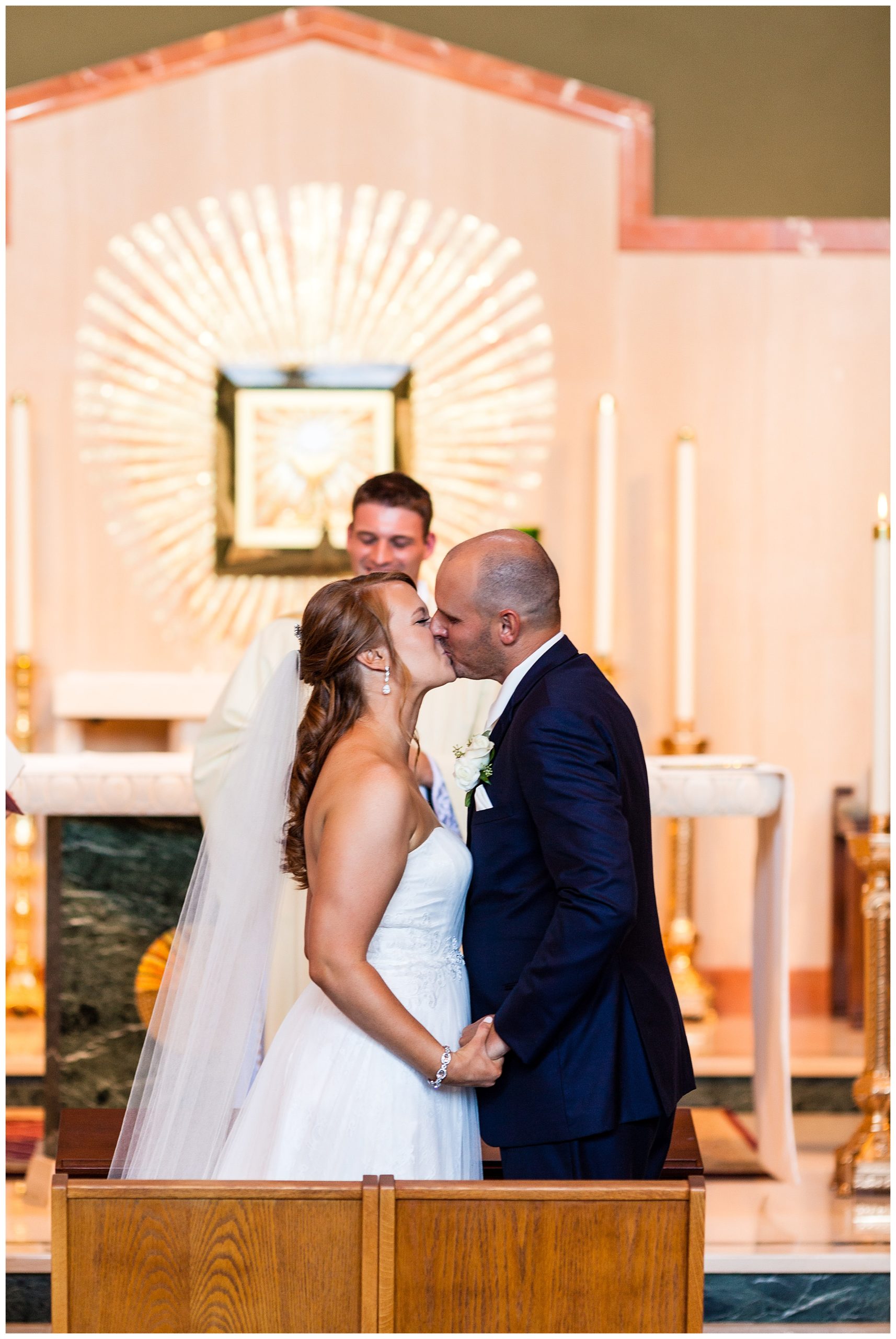 Bride and groom kiss at alter in St. Andrew's Church wedding ceremony