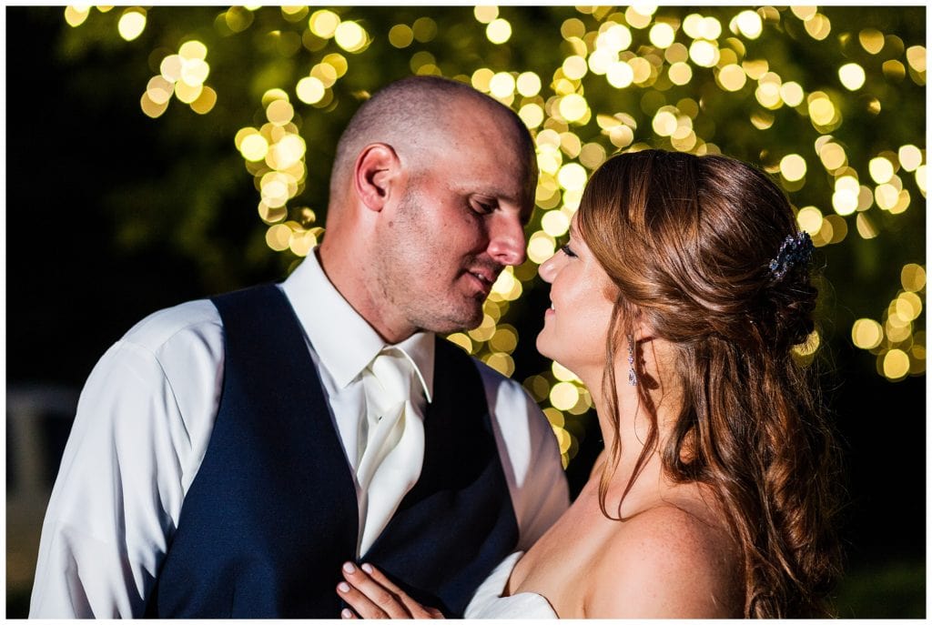 Nighttime bride and groom portrait with bokeh tree lights in background at William Penn Inn wedding reception