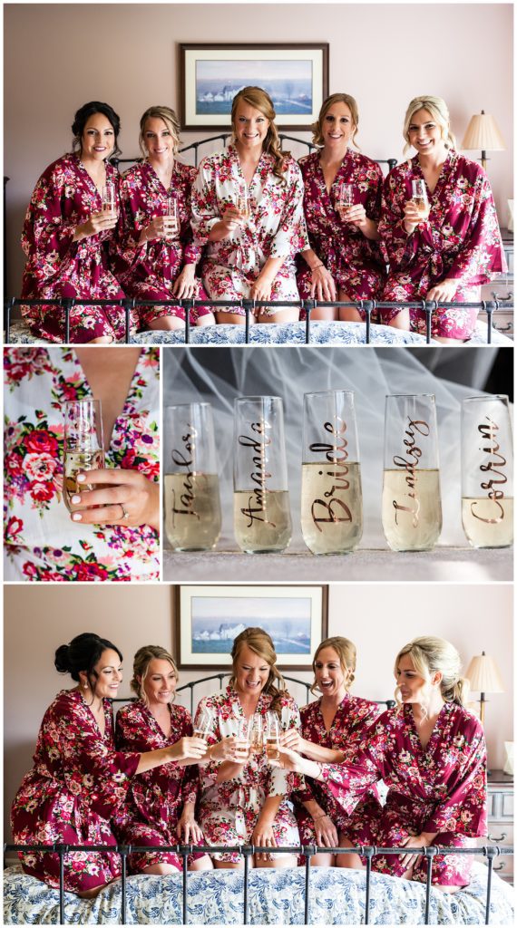 Bridesmaids and bride in matching red floral robes toasting personalized champagne glasses on bed