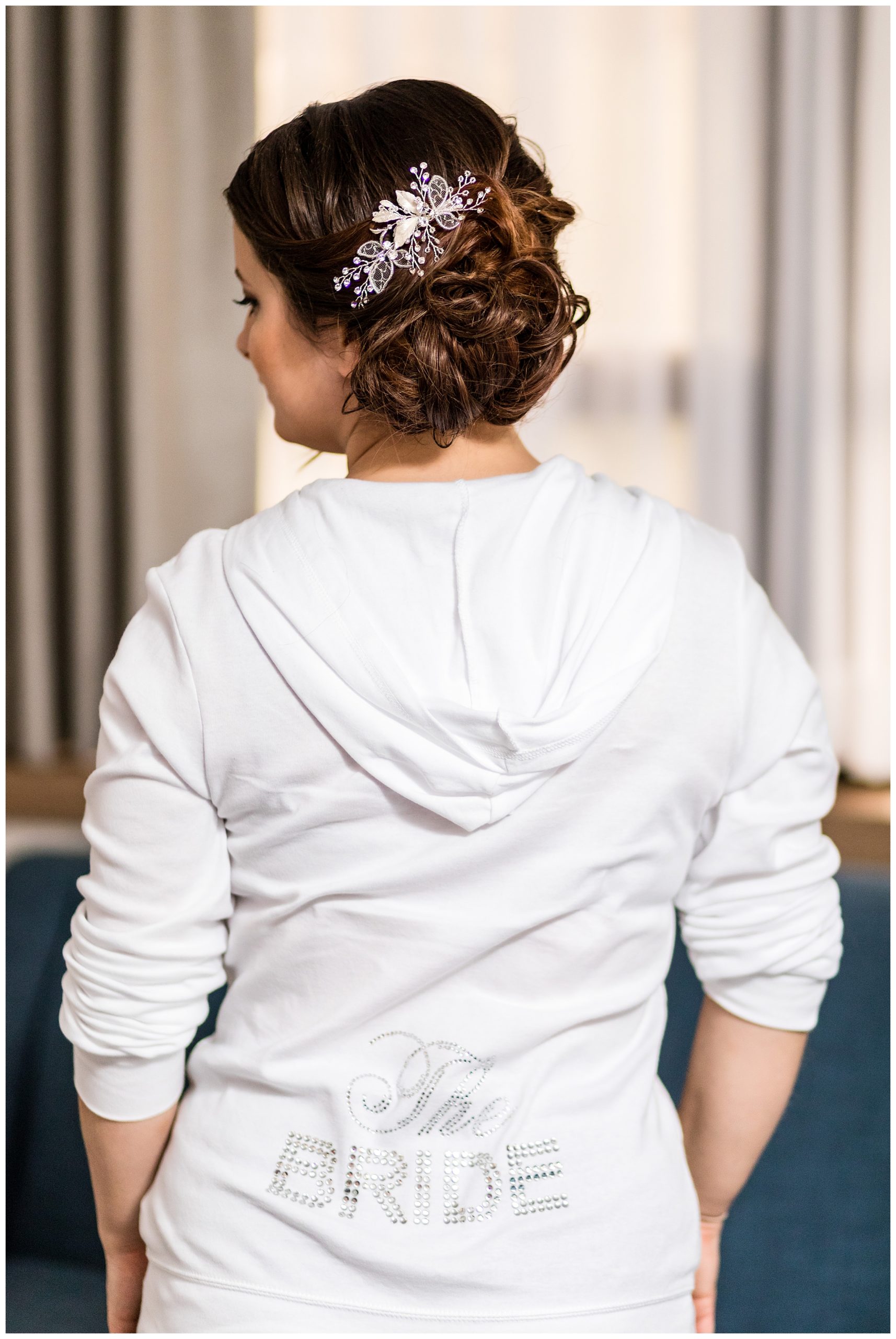 Bride in 'the bride' bedazzled white hoodie with wedding hair and white hair pin