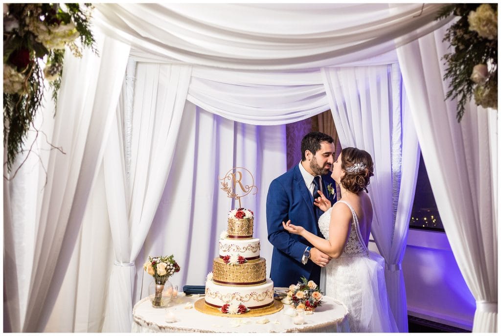 Bride and groom kiss after cutting cake at Radnor Hotel wedding reception