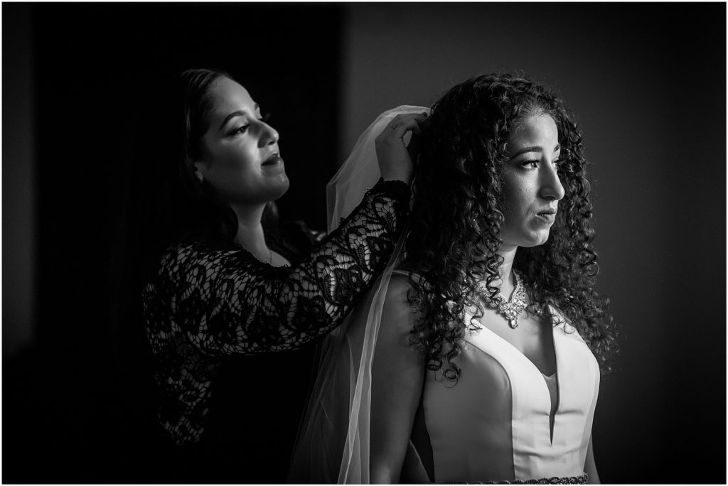 Black and white Window lit portrait of bride getting veil pinned in hair before micro Penn Museum wedding