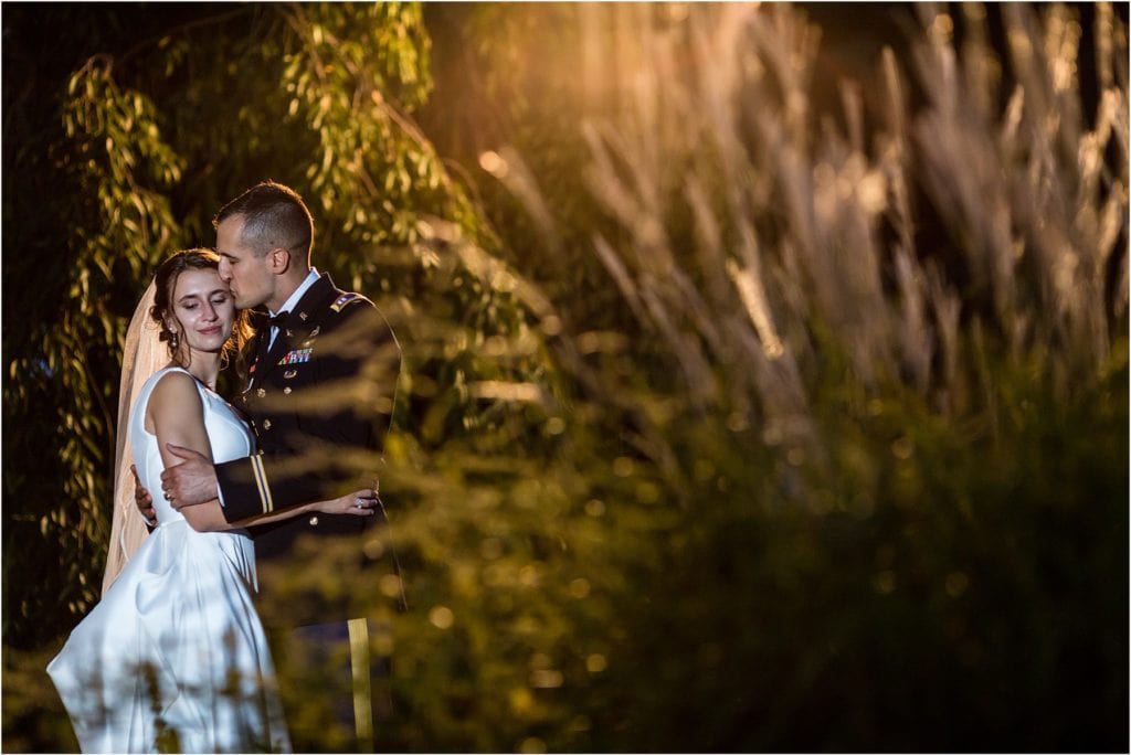 Night portrait of groom kissing bride on cheek in garden at Mountain Springs Lake Resort wedding reception