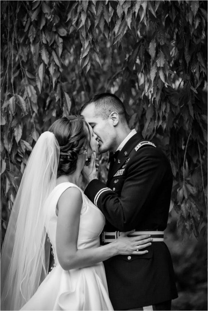 Black and white portrait of bride and groom kissing under low hanging tree branches at Mountain Springs Lake Resort wedding
