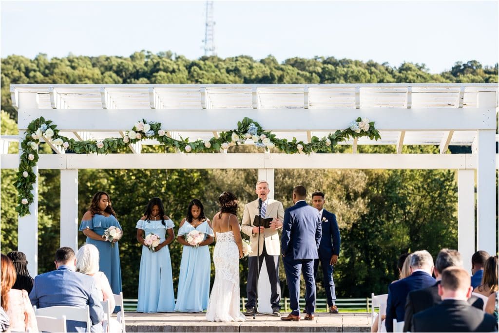 Husband and wife stand at alter with their children as they renew vows for 25th wedding anniversary at Barn at Stoneybrooke