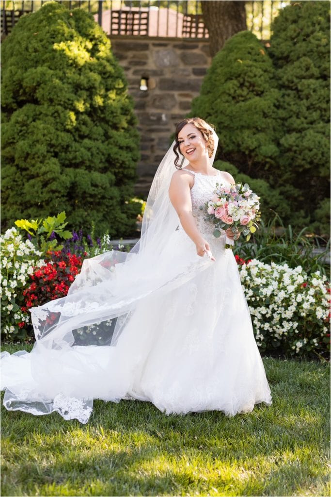 Bride twirling with long dress train and veil in church garden