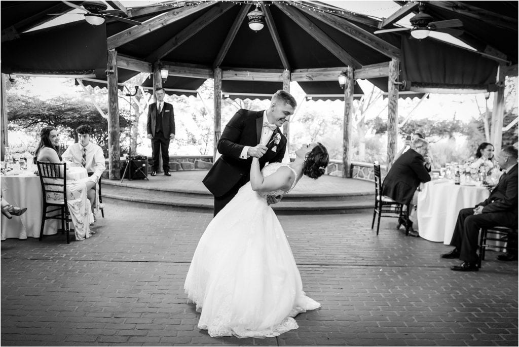Black and white portrait of groom dipping bride during first dance on outdoor dance floor at Joseph Ambler Inn intimate wedding reception