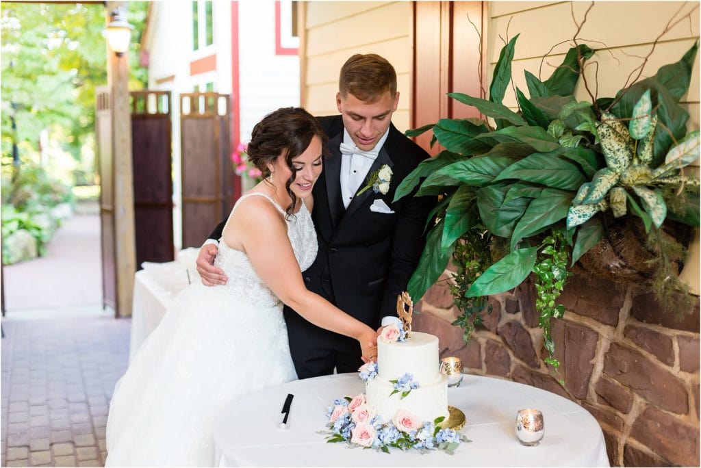 Bride and groom cut floral detailed cake at Joseph Ambler Inn intimate wedding reception