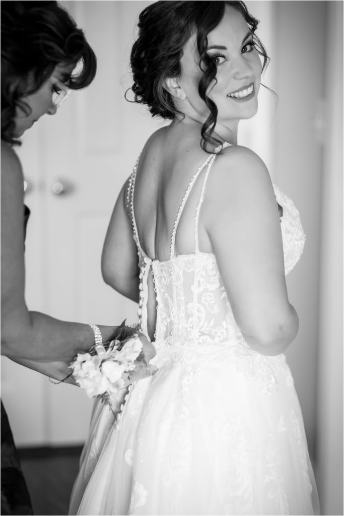 Black and white bridal portrait of mother buttoning up gown