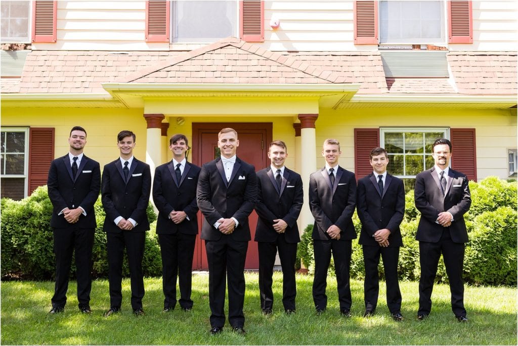 Groomsmen in black tuxedos portrait in front of house