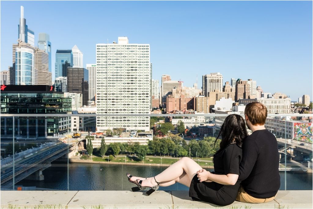 Couple sitting on ledge at Circa Green overlooking Center City Philadelphia in engagement session