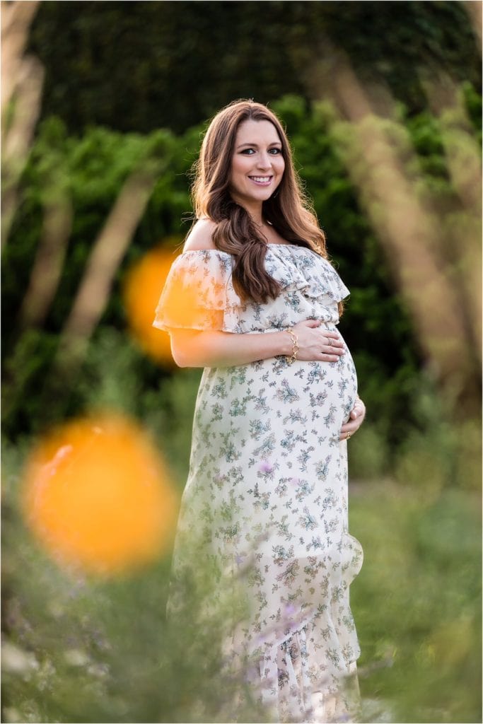 Traditional maternity session portrait of mother standing in field at Longwood Gardens