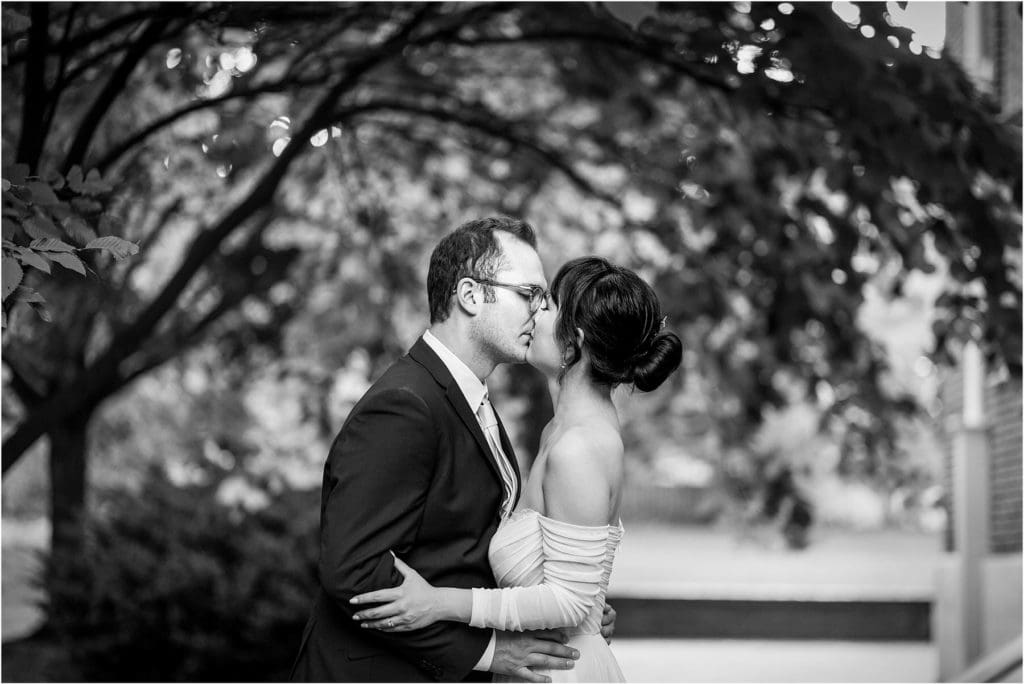 Black and white portrait of bride and groom kissing under trees in Old City Philadelphia intimate wedding