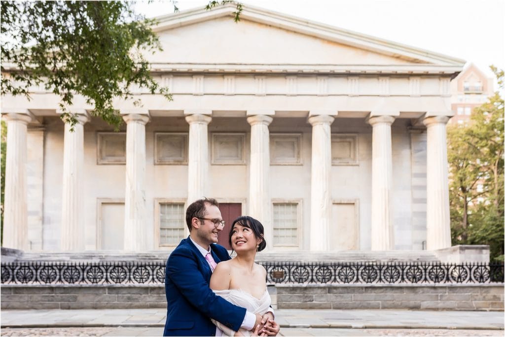 Romantic portrait of bride looking at groom over her shoulder in front of the First National Bank in Philadelphia