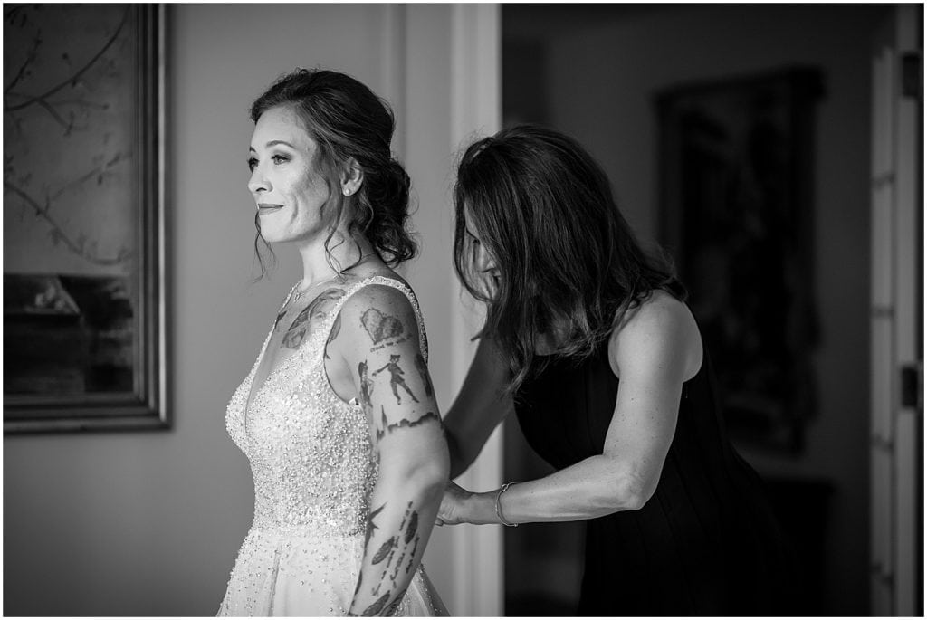 Black and white portrait of mother of the bride buttoning brides dress at Bolingbroke Mansion wedding