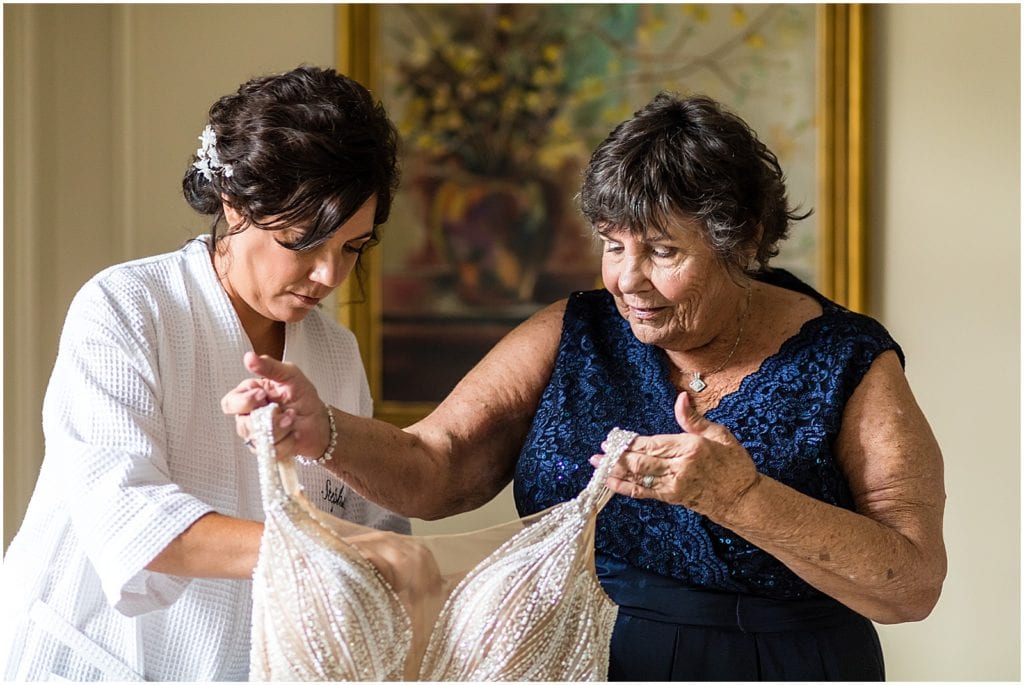 Mother of bride helping bride into wedding gown before same sex pride wedding