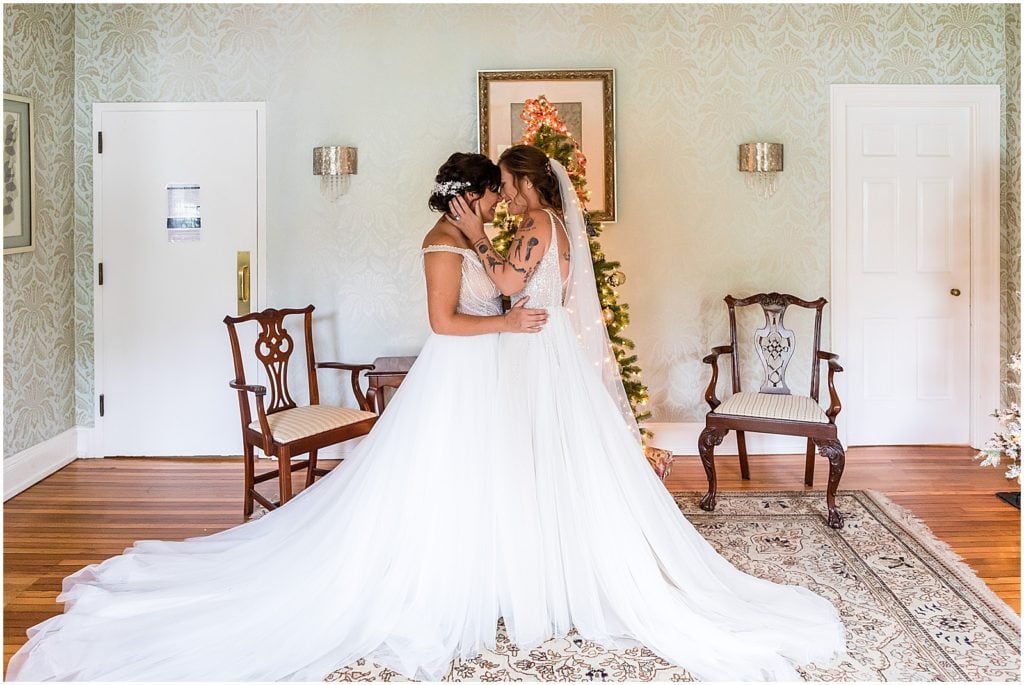 two brides smile after pulling away from a kiss at first look before Bolingbroke Mansion same sex pride wedding