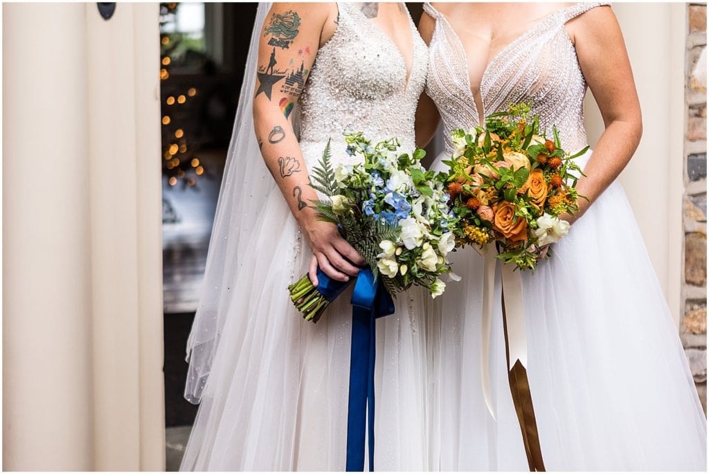 Same sex pride wedding detail of brides orange and blue bouquets