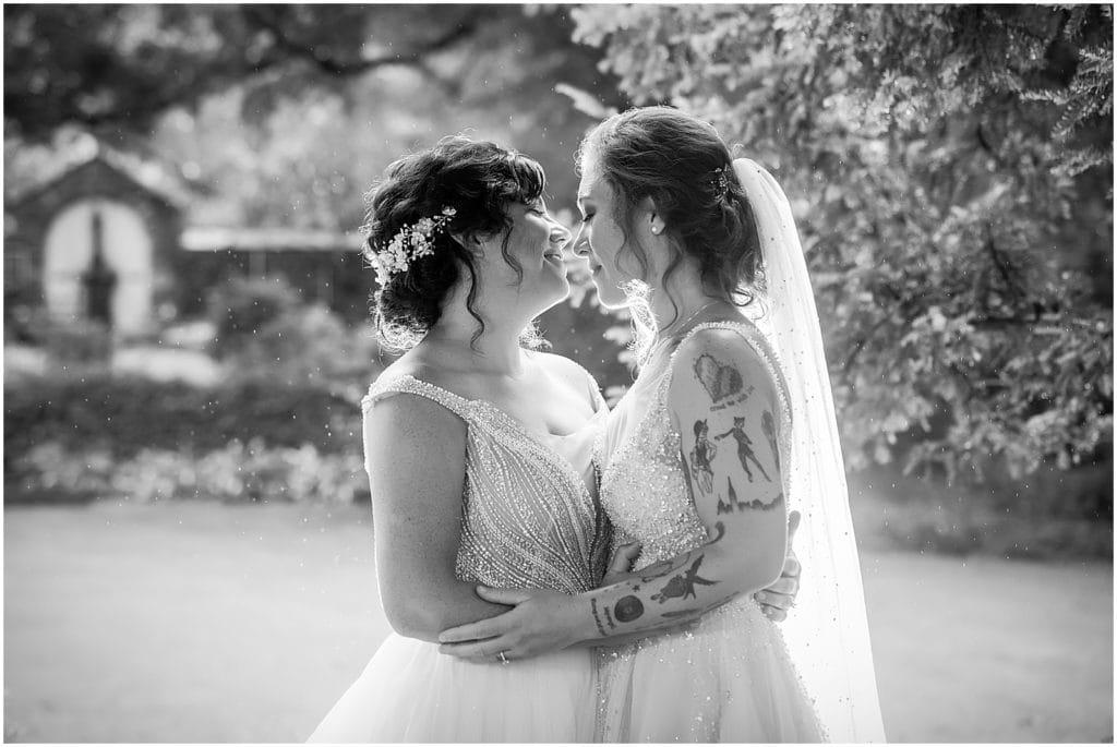 Black and white portrait of brides pulling away from a kiss in gardens at Bolingbroke Mansion Pride wedding