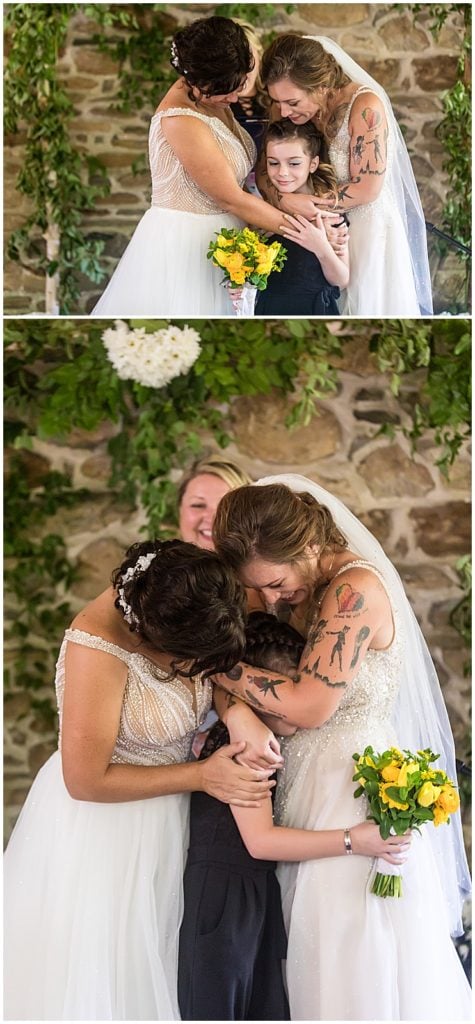 Brides stand with and hug daughter at alter during wedding ceremony at Bolingbroke Mansion