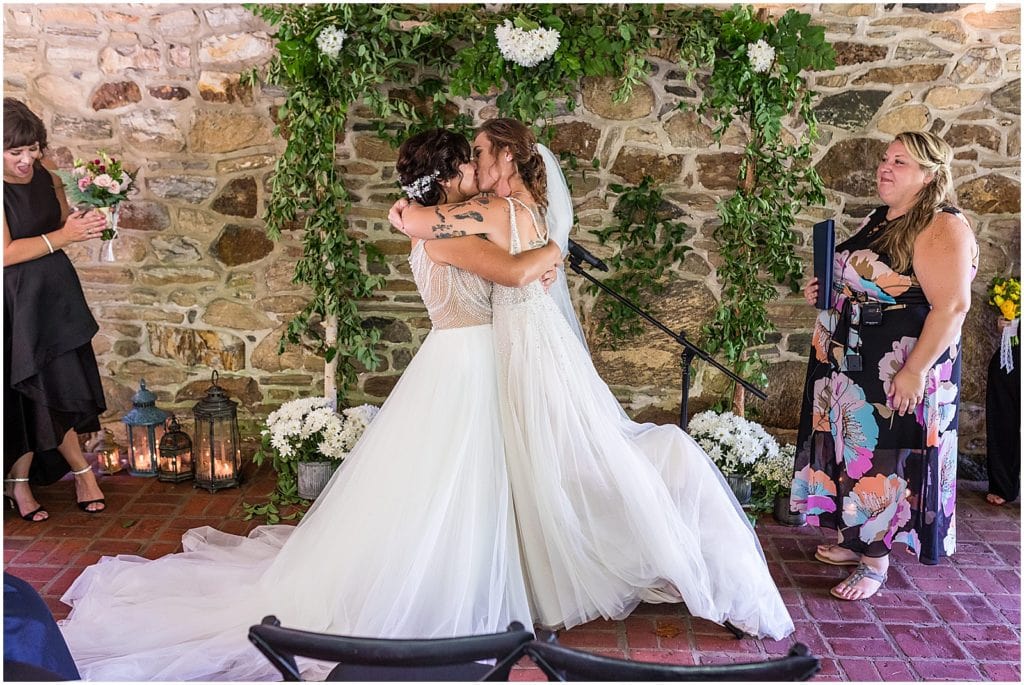 Brides kiss at alter during same sex pride wedding ceremony at Bolingbroke Mansion