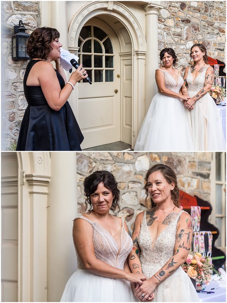 Brides hold hands and tear up during speeches at Bolingbroke Mansion same sex wedding reception