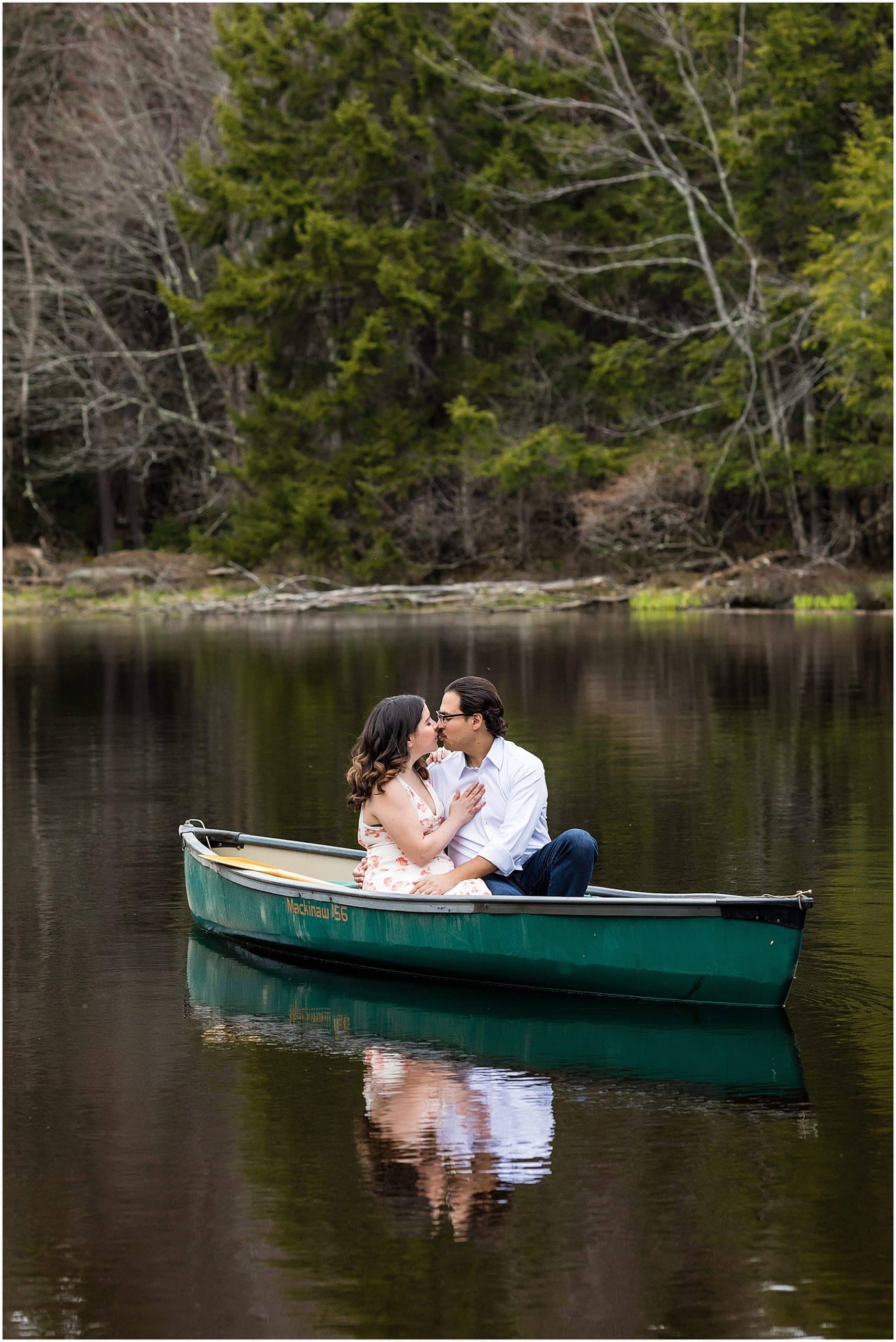 Engagement session portrait of couple kissing on canoe on lake in the Poconos