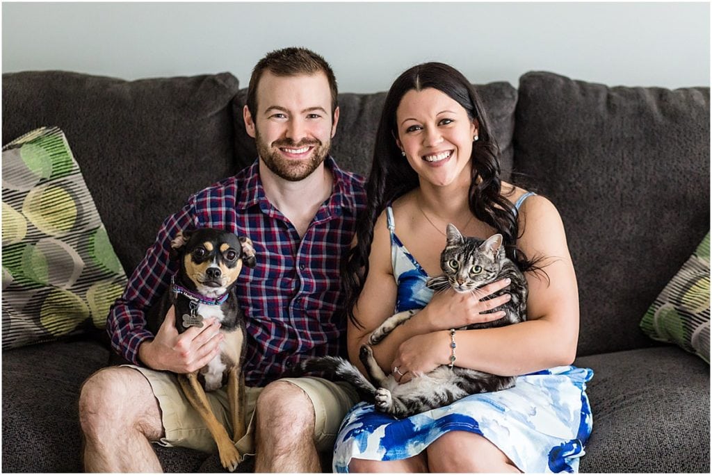 A couple holds their dog and cat while sitting on their couch at their home in Philadelphia