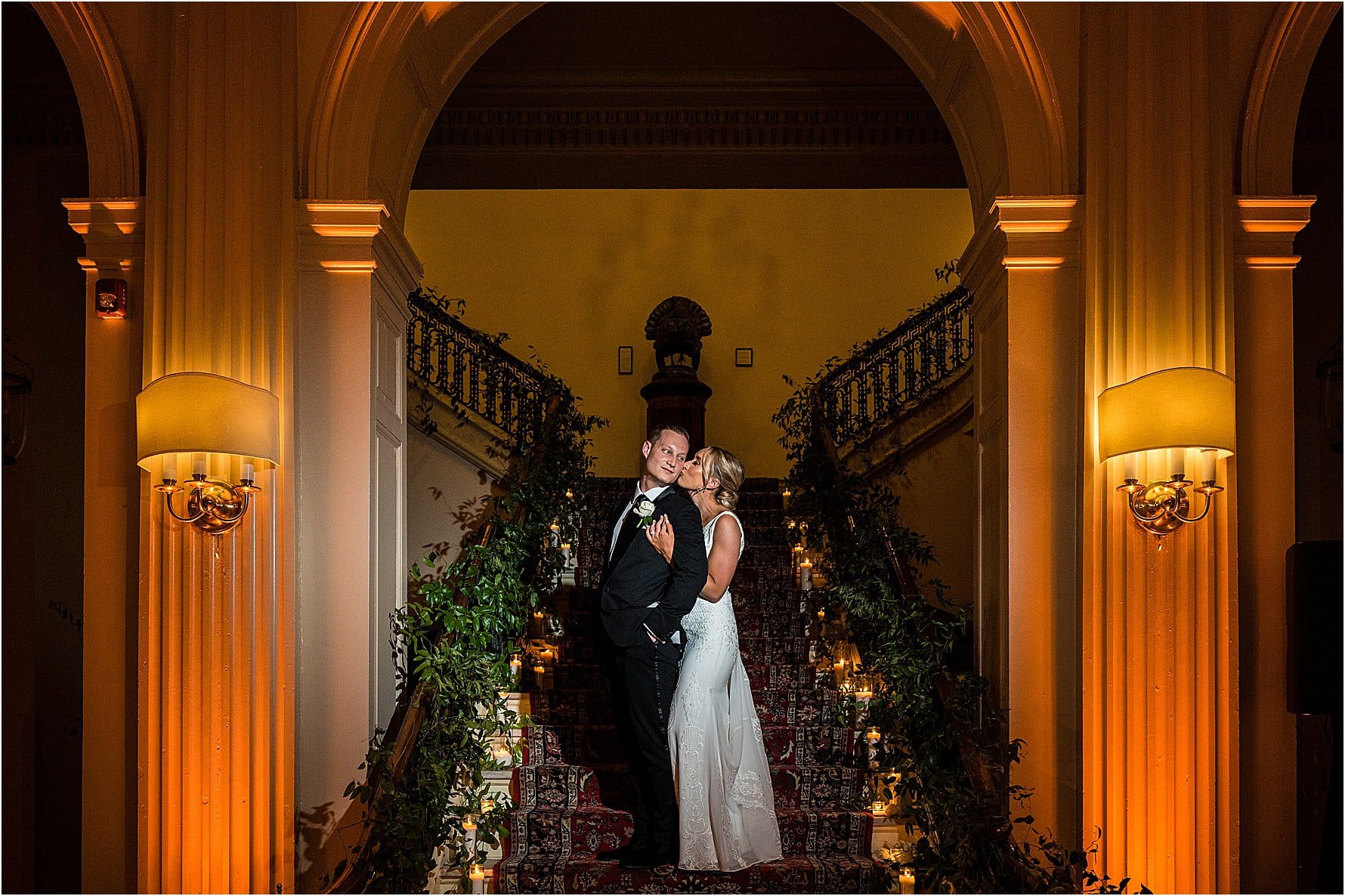 Bride kisses groom from behind on stairs