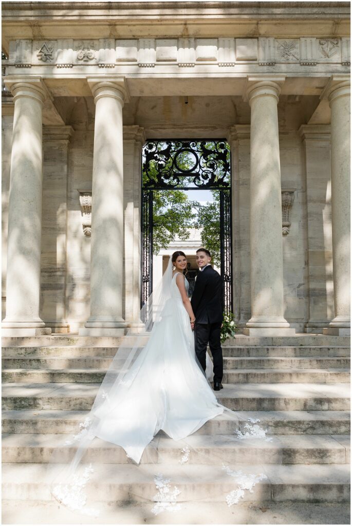 Newlyweds (with bride in cathedral-length veil) pose on the steps of Philadelphia's Rodin Museum
