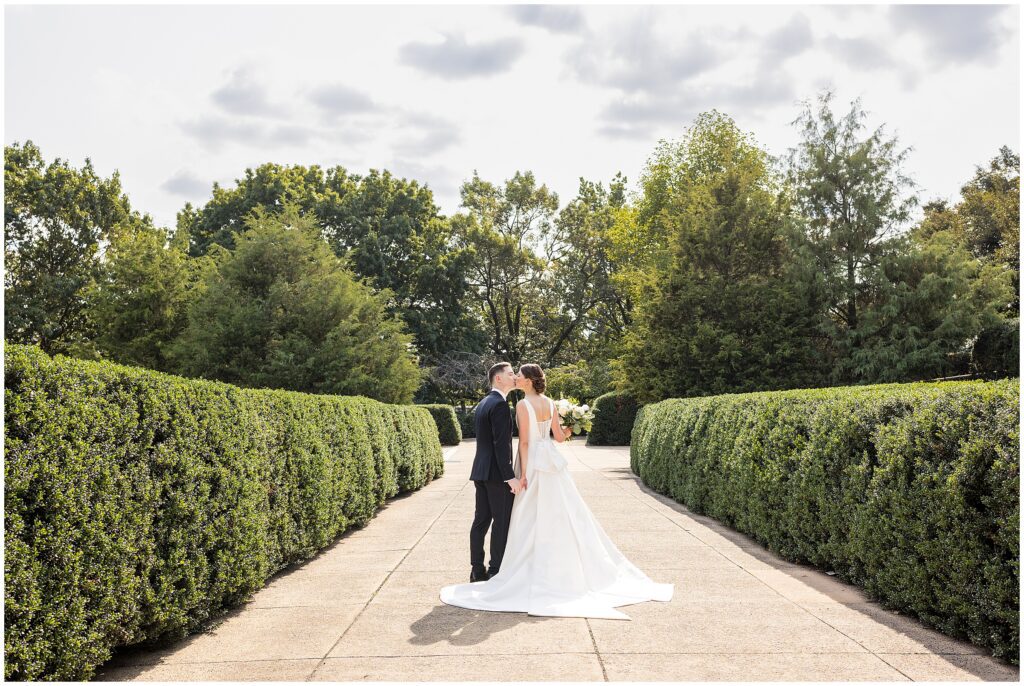 Bride and Groom hold hands and kiss while walking away from the camera 