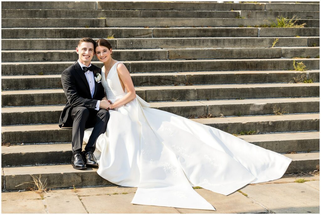 Newlyweds sit on the iconic Rocky stairs at the Philadelphia Museum of Art in their wedding attire
