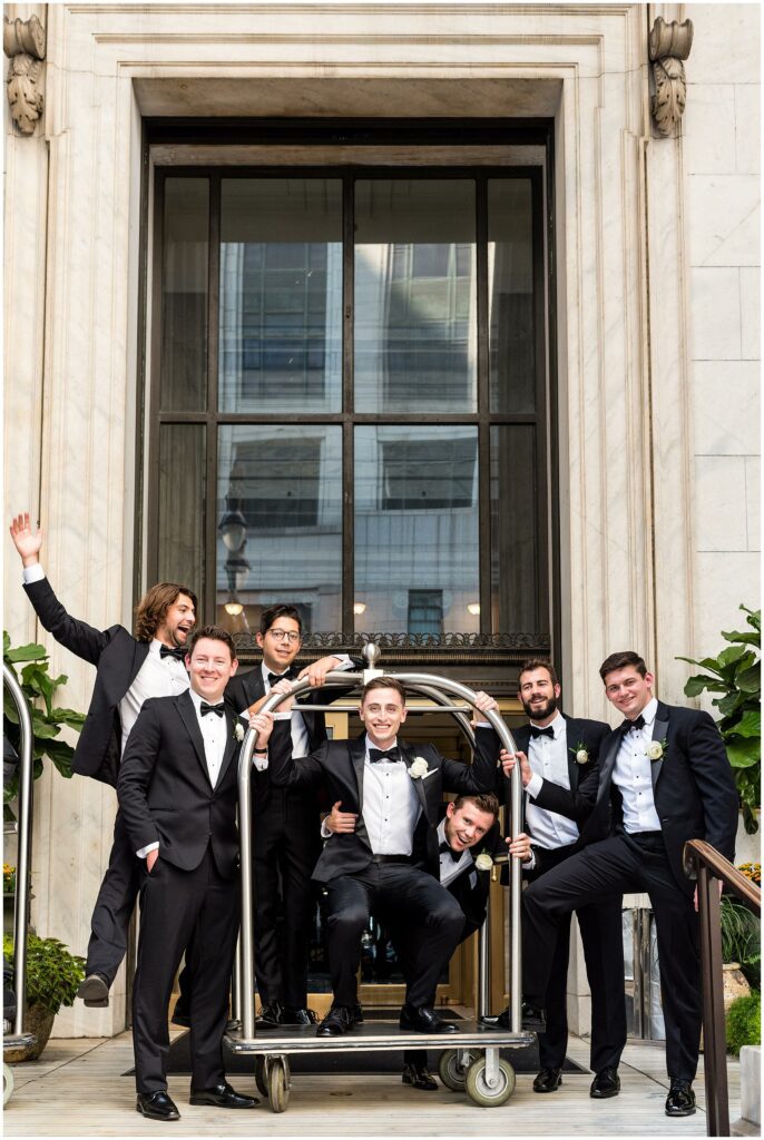 Groom and his wedding party on luggage rack before wedding at Philadelphia's Ritz-Carlton