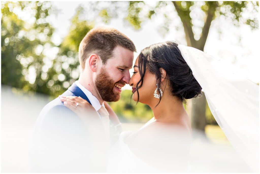 Bride and groom softly touch their noses together 