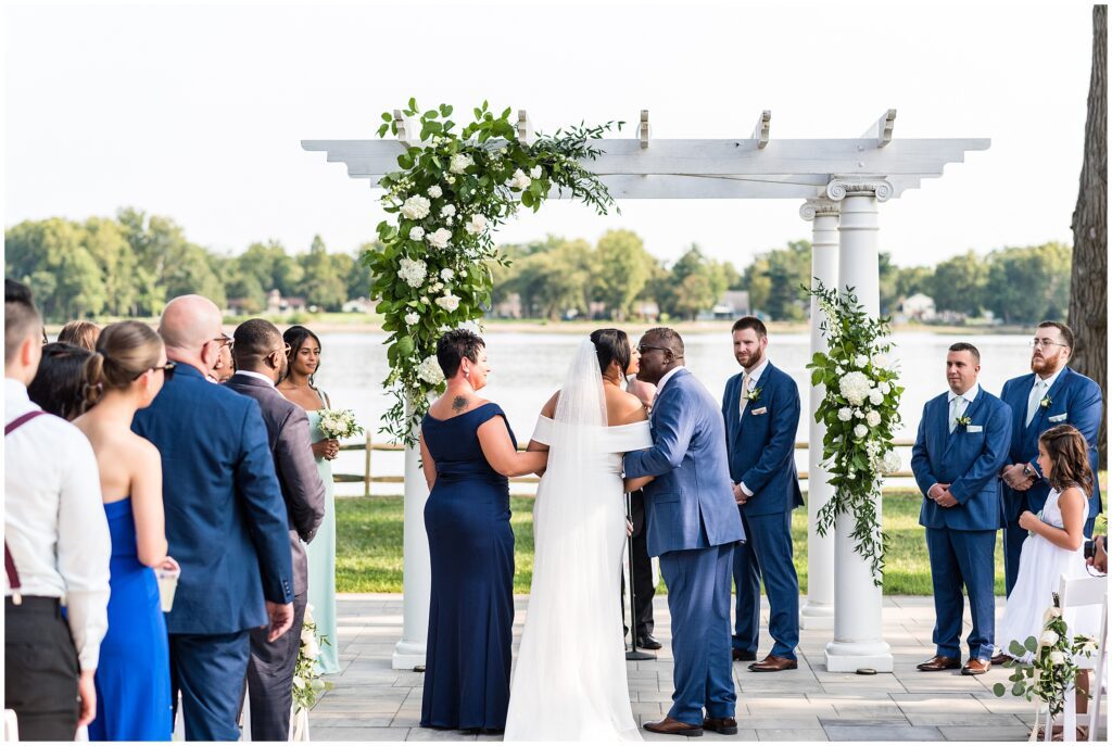 Bride is kissed by her father as her parents are by her side as they approach her groom during wedding ceremony