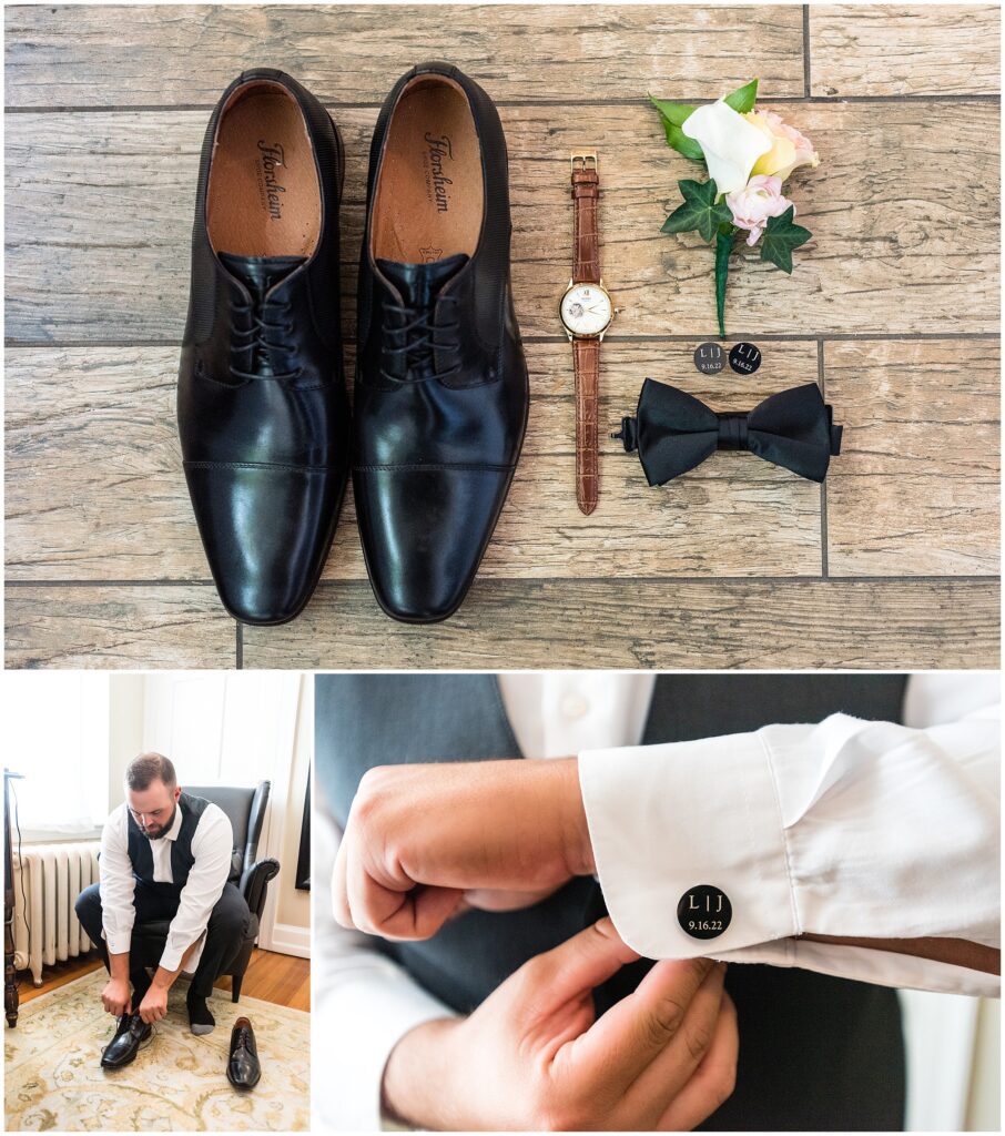 Groom details, including black shoes, watch with brown wristband, custom cufflinks with wedding date, black bowtie, and white and blush boutonniere