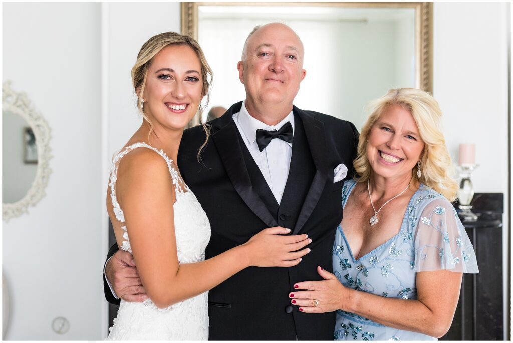 Bride stands with her father who is emotional after first look, and mom