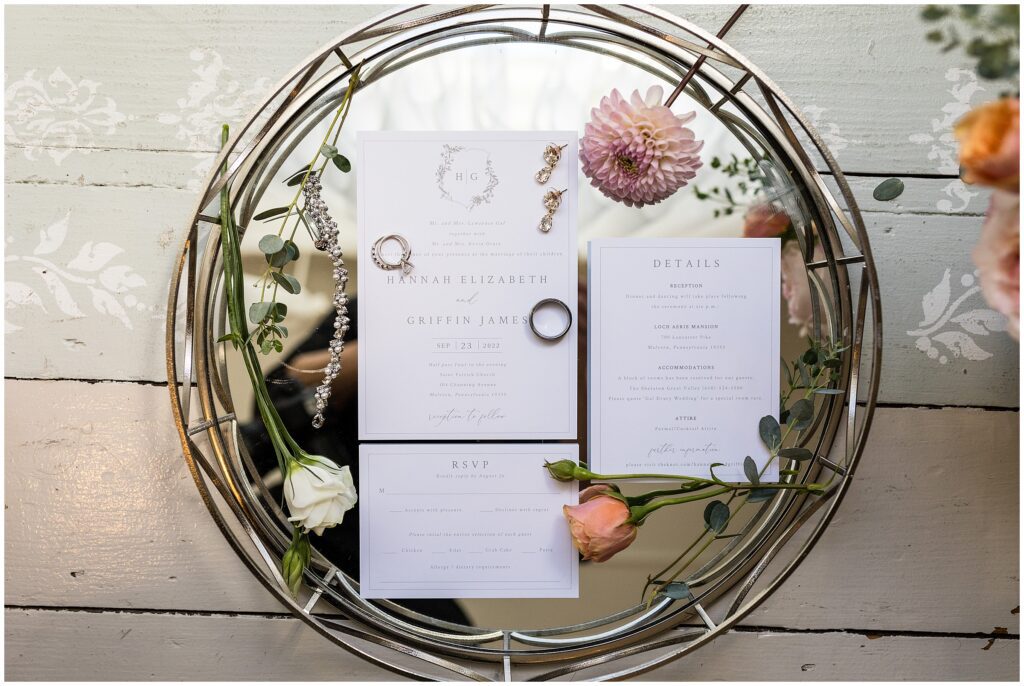 classic wedding invitations on mirror tray with floral details and jewelry