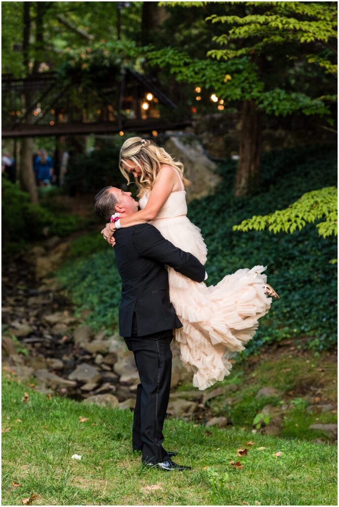 Groom lifts his Bride on the lush green grounds at Pomme Radnor