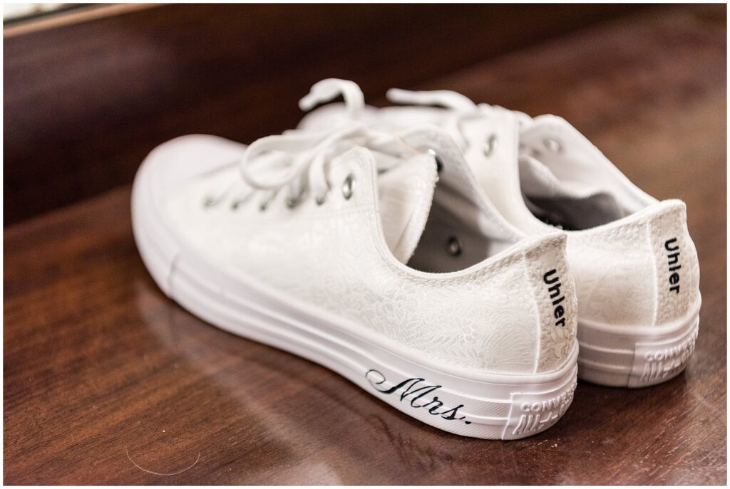 white floral-patterned sneakers with "Mrs." written in black calligraphy on the bottom, and the bride's last name embroidered on the heels